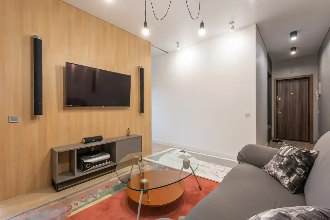 Modern living room with gray sofa, glass coffee table, wall-mounted TV, and wood accent wall for home decor