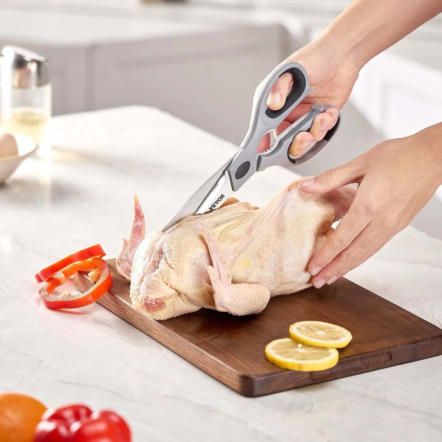 Household items Kitchen Items: person using kitchen scissors to cut chicken on a cutting board with vegetables.