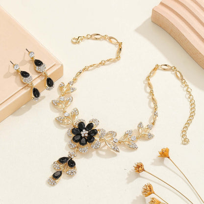 Vintage jewelry set featuring a black alloy necklace with floral design and matching earrings on a light background.