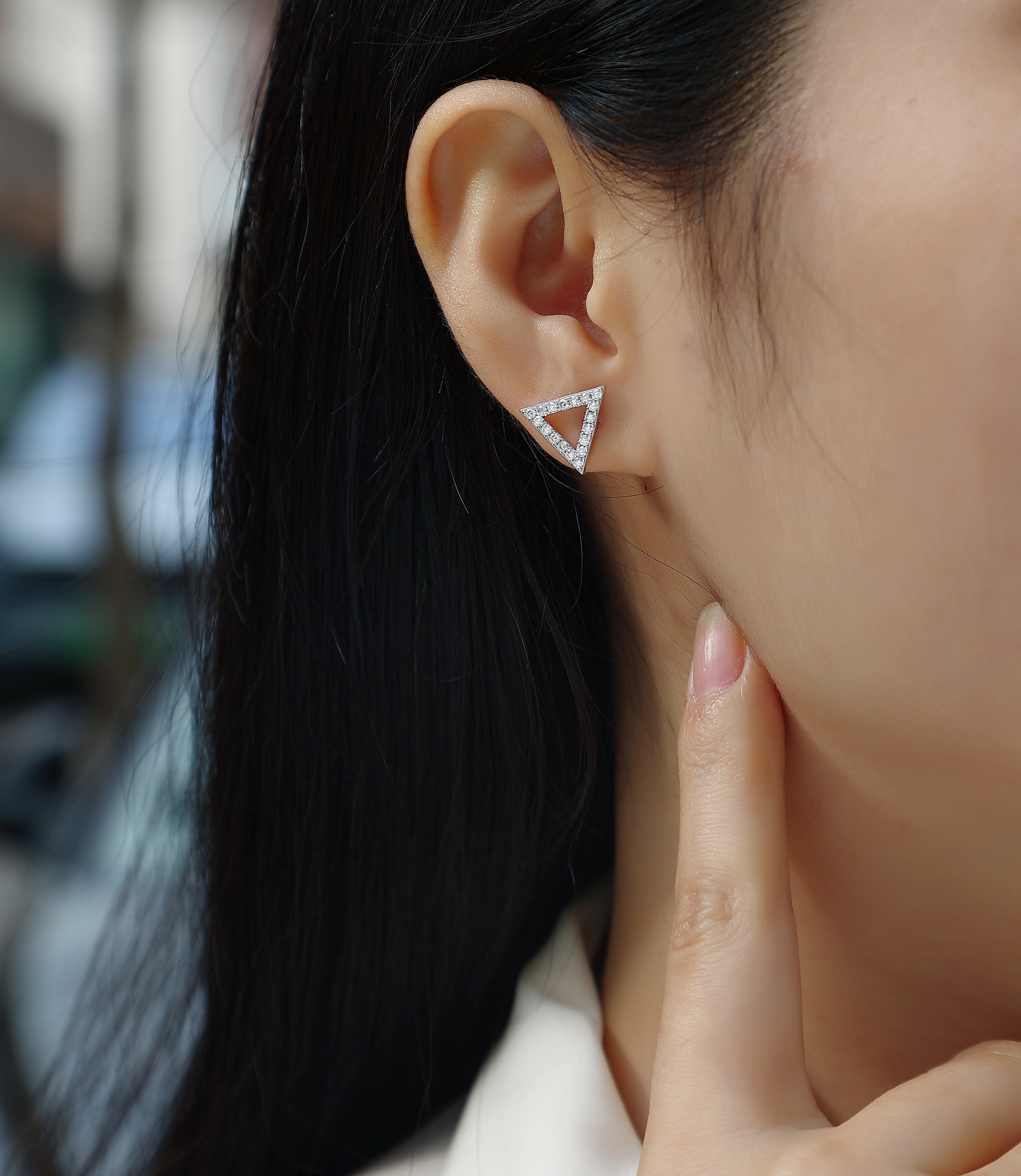 Moissanite stud earrings in triangle design worn by a woman, showcasing trendy and fashionable jewelry.
