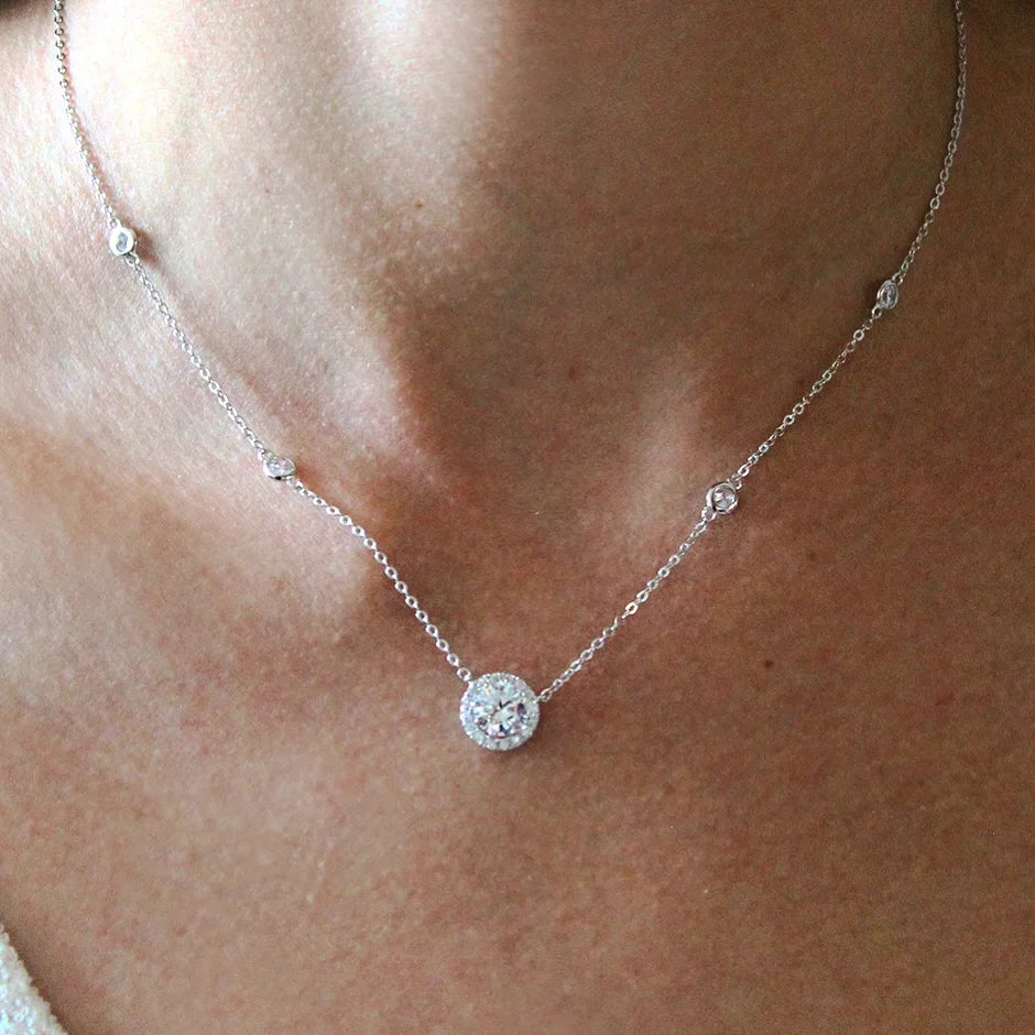 Silver necklace with a round pendant on a person's neck